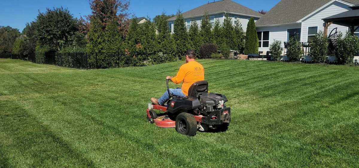 Crew member mowing a residential lawn